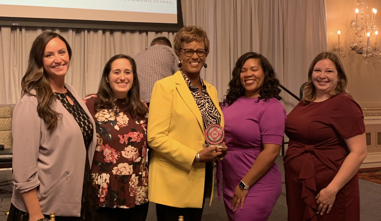 Laurna with team holding an award